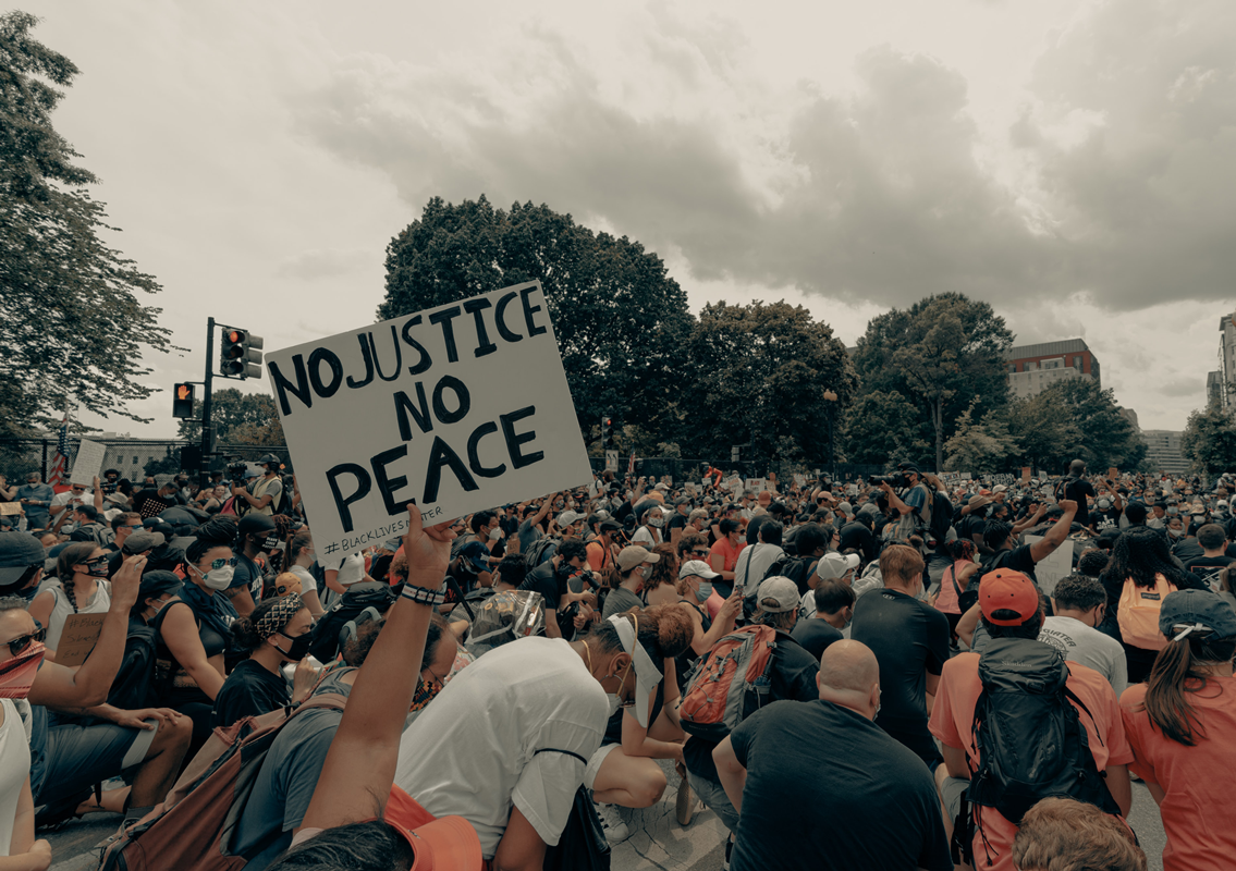 Black Lives Matter protest. Multitude of people gathered (all ages, races and genders), a sign says " No Justice, No Peace"