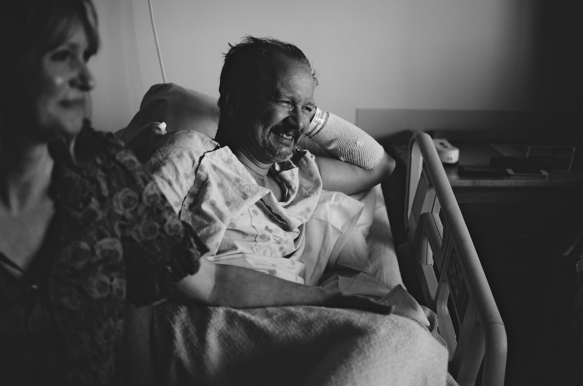 Black and white photograph of patient in a hospital bed with a woman from his family (maybe his wife) on his side