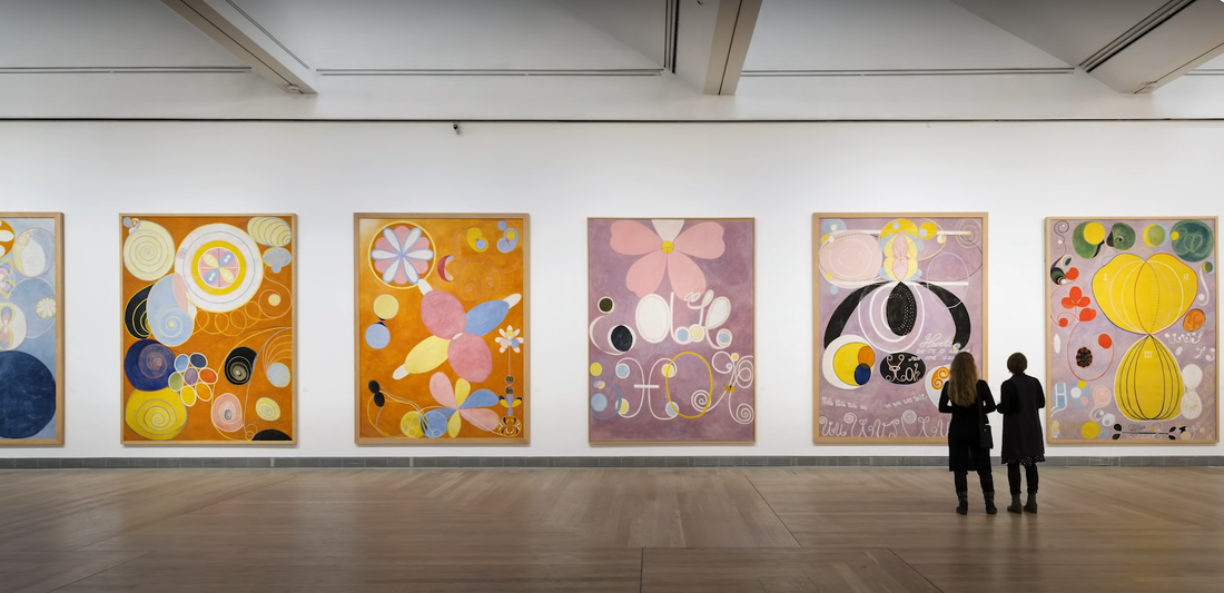 Two people in an art gallery, looking at the artworks