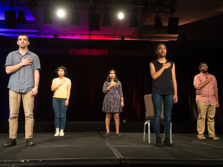 Students stand with their hands over their hearts while performing